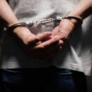Arrested man in handcuffs with handcuffed hands behind bac
