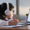 Little girl attending to online school class on laptop computer