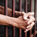 Hands of prisoner in jail background