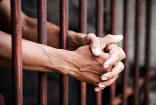Hands of prisoner in jail background