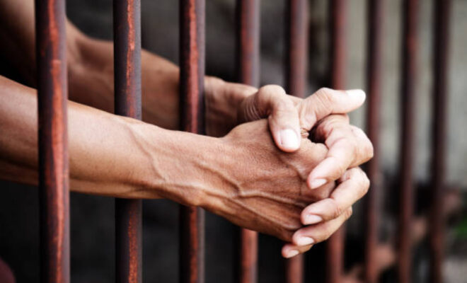 Hands Of Prisoner In Jail Background