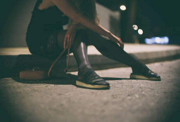 Drunk Woman In Dress Sits On The Roadside At Night.