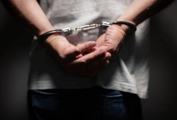 Arrested man in handcuffs with handcuffed hands behind bac