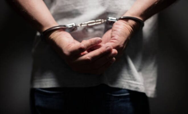Arrested man in handcuffs with handcuffed hands behind bac