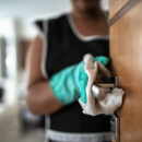 Hands with glove wiping doorknob