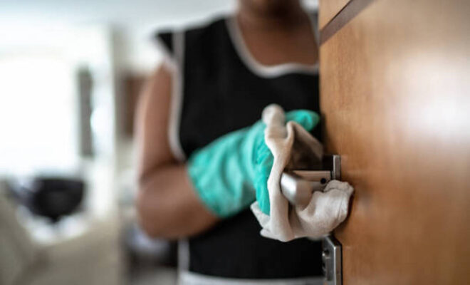 Hands with glove wiping doorknob